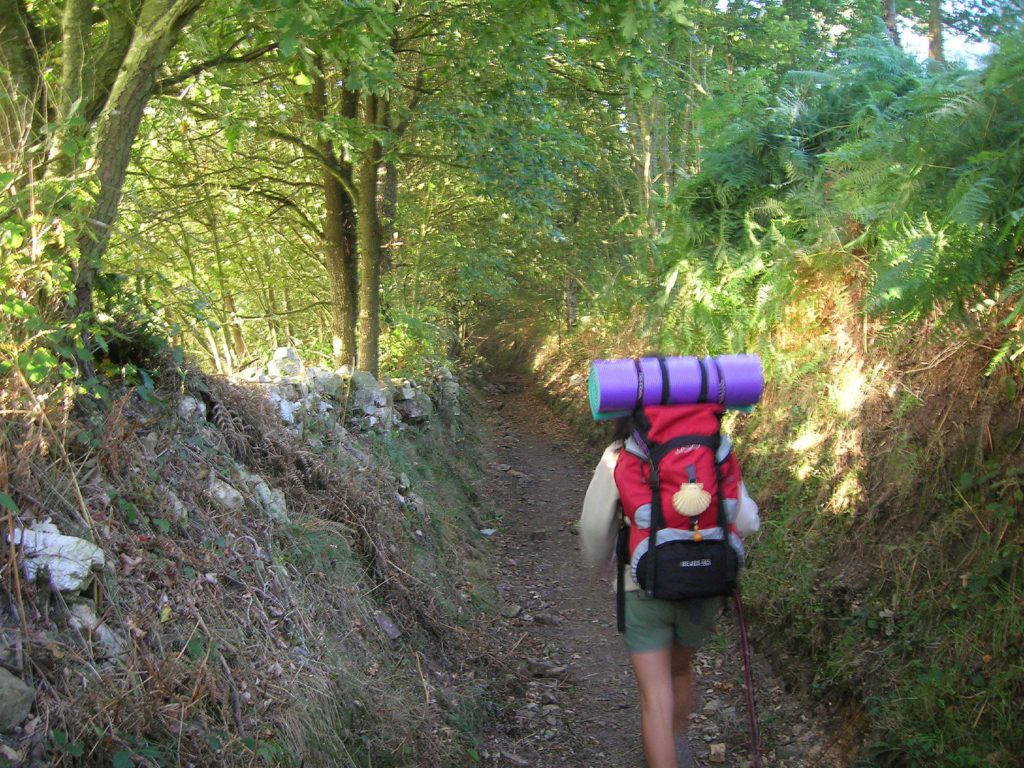 Peregrino con mochila atravesando un monte en el Camino de Santiago en Asturias